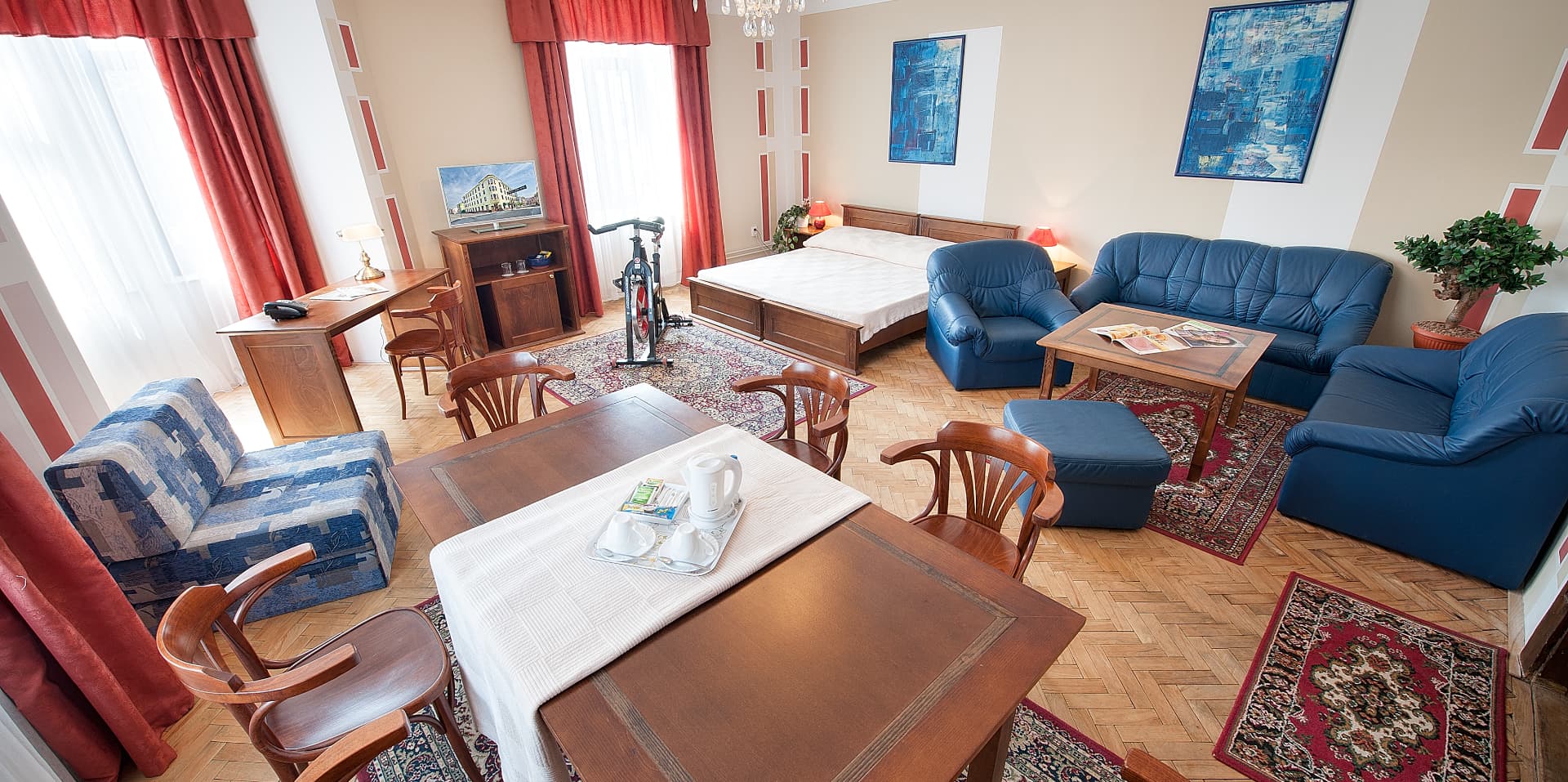 Junior Suite — Obývací část se sedací soupravou, pracovním stolem a spinningovým kolem